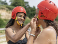 Woman helping friend putting on sports helmet