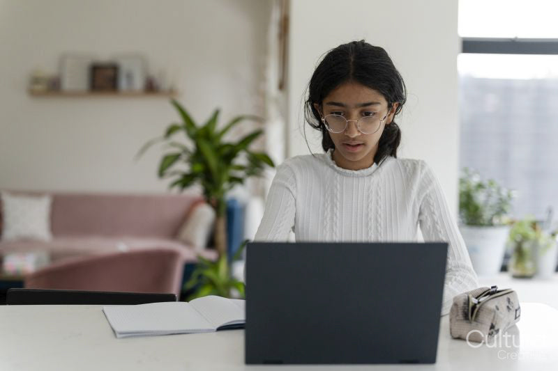 Girl doing homework and using laptop in living room