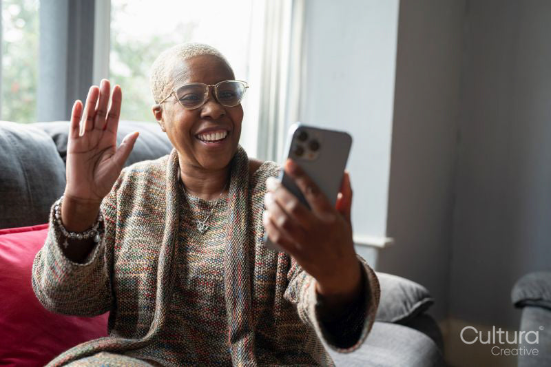 Mature woman sitting in living room with her smart phone