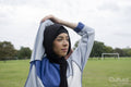 Portrait of woman in hijab stretching arm in park