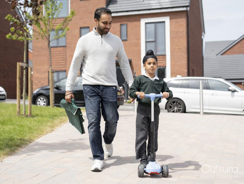 Boy on push scooter walking with father to school