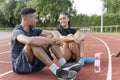 Couple of athletes resting at sports track after training