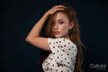 Woman in a polka dot top posing with hand on head