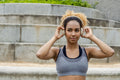 Sporty young woman putting on headphones