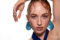 Studio portrait of a woman in a blue dress and large blue earrings