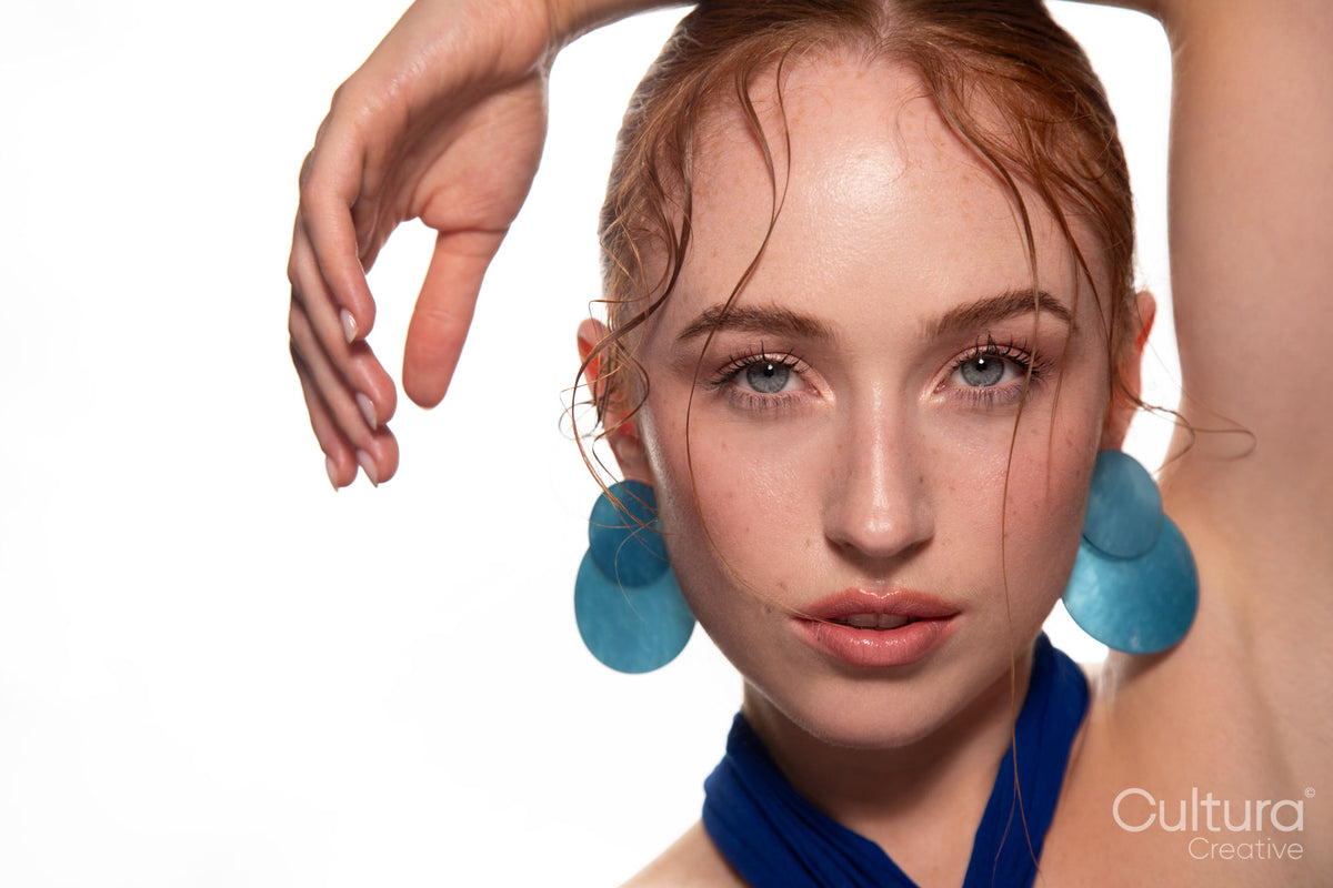 Studio portrait of a woman in a blue dress and large blue earrings