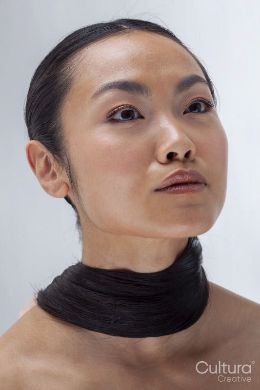 Studio portrait of woman with hair wrapped around neck