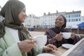 Two Muslim women drinking coffee in sidewalk cafe