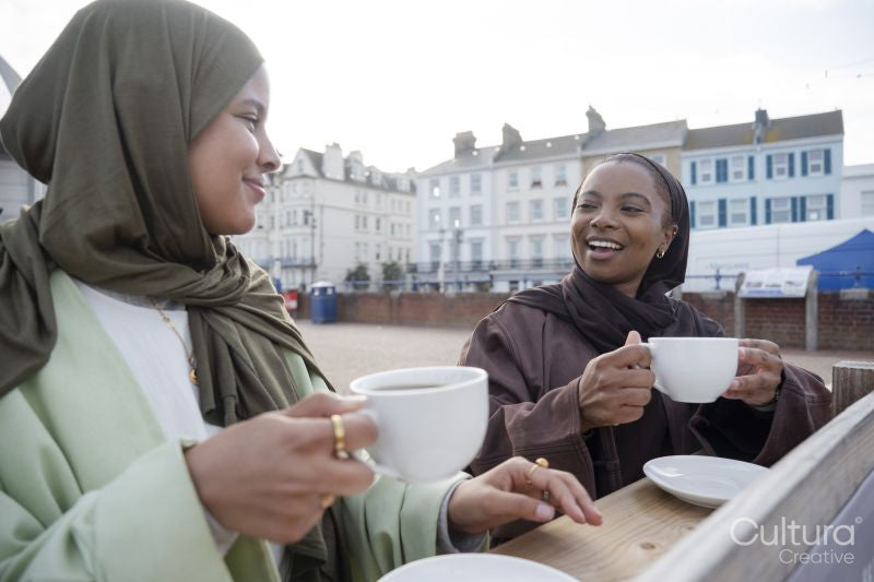 Two Muslim women drinking coffee in sidewalk cafe