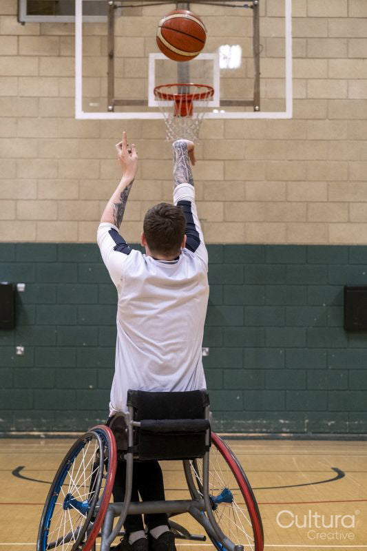Male basketball player in wheelchair shooting ball