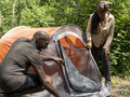 Mature couple setting up tent in forest