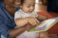 Mother reading to baby daughter at home