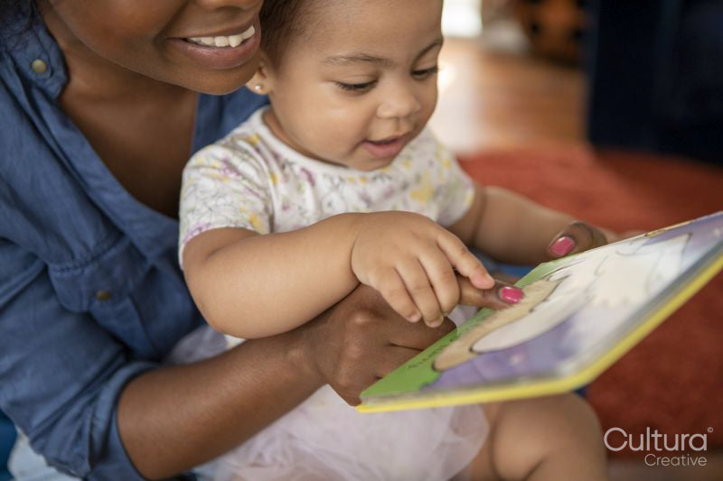 Mother reading to baby daughter at home