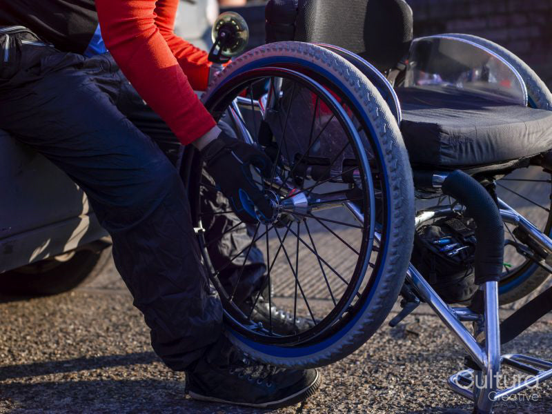 Low section of disabled man setting up handcycle at car