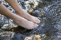 Bare feet of woman in shallow stream