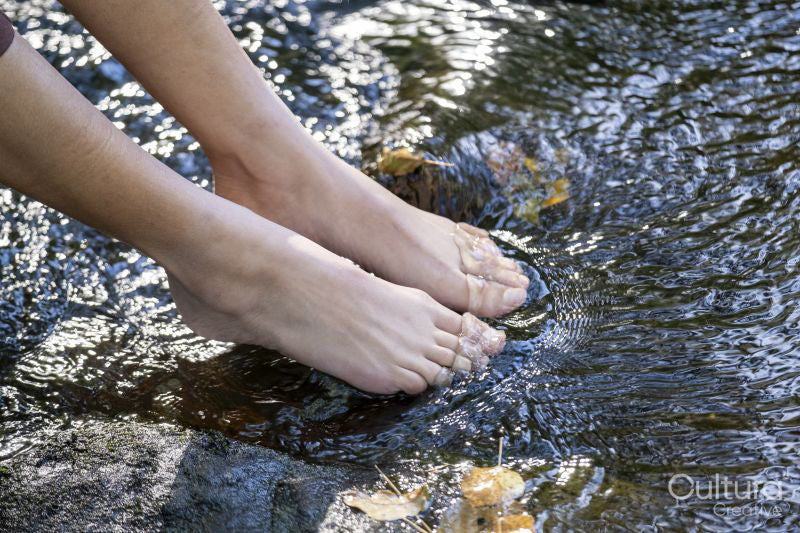 Bare feet of woman in shallow stream