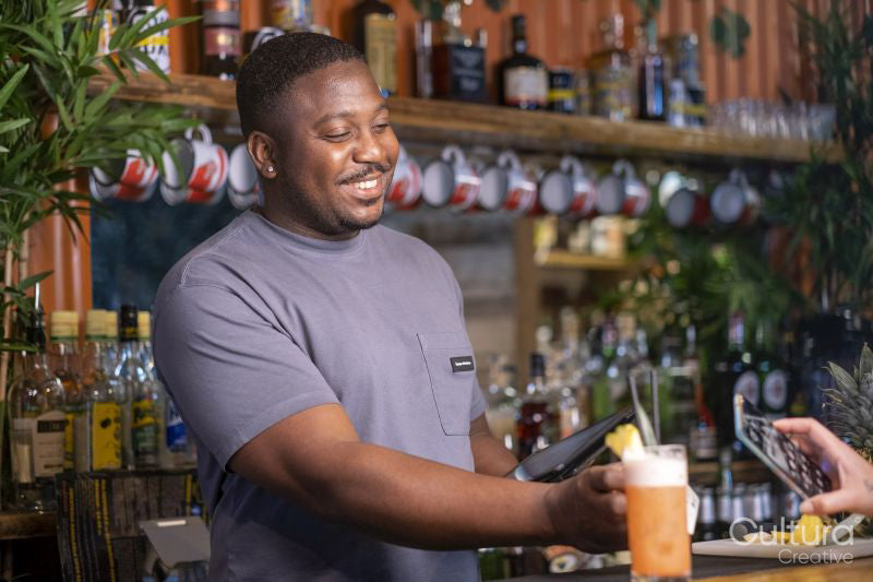 Smiling bartender with credit car reader and tablet at bar, USUN wiek kobiety