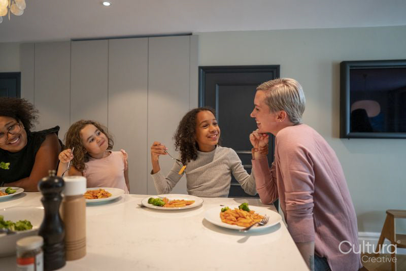Mother with three daughters enjoying dinner in kitchen
