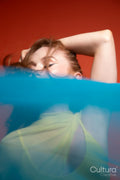 Woman in yellow dress veiled by blue sheer fabric