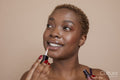 Studio portrait of woman applying lip gloss