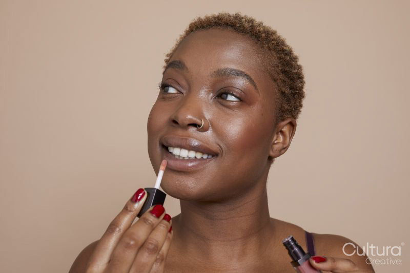 Studio portrait of woman applying lip gloss