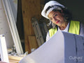 Woman in hardhat looking at blueprint