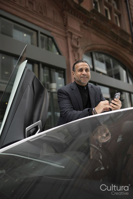 Mature man standing by luxury car and using phone