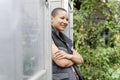 Portrait of smiling woman standing in front of greenhouse