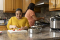 Woman with down syndrome preparing food with mother in kitchen