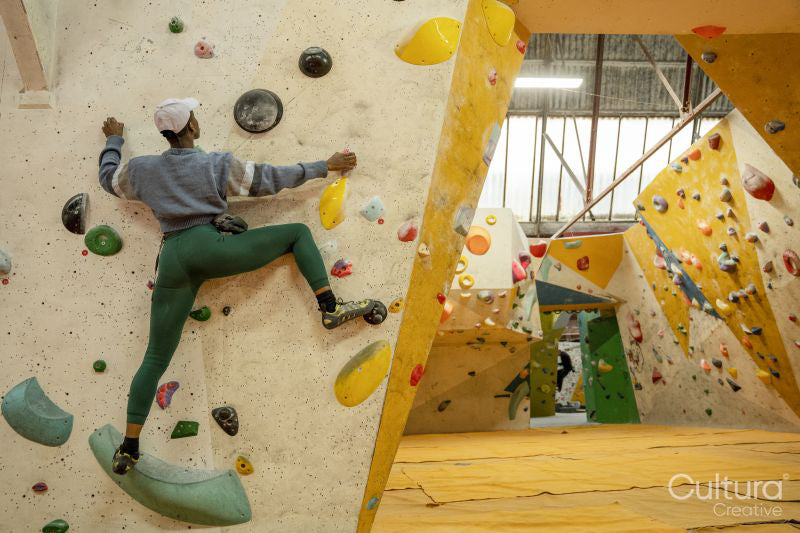 Rear view of athletic woman on climbing wall at gym