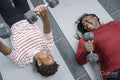 Mother and daughter doing weight training with dumbbells on mat in gym