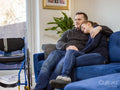 Smiling couple sitting on sofa next to wheelchair