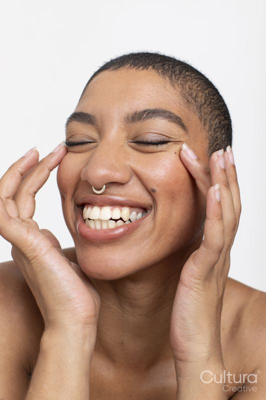 Studio portrait of smiling woman with nose ring touching face