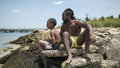 Father and son sitting on rocks on beach