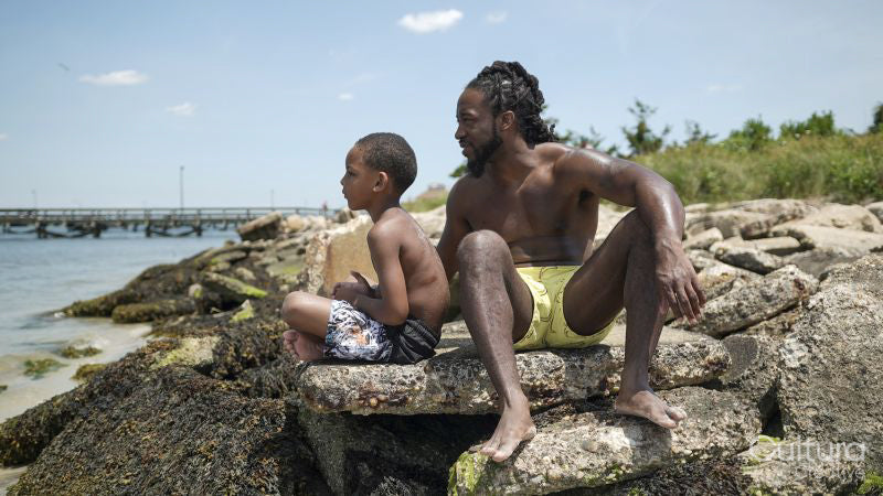 Father and son sitting on rocks on beach