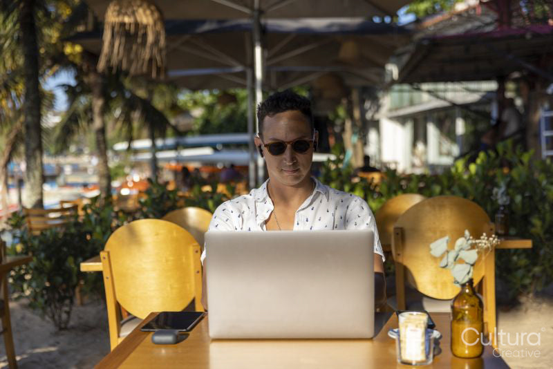 Man using laptop at beach cafe