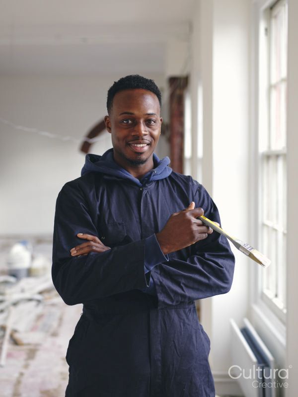 Portrait of smiling man holding paintbrush during renovation