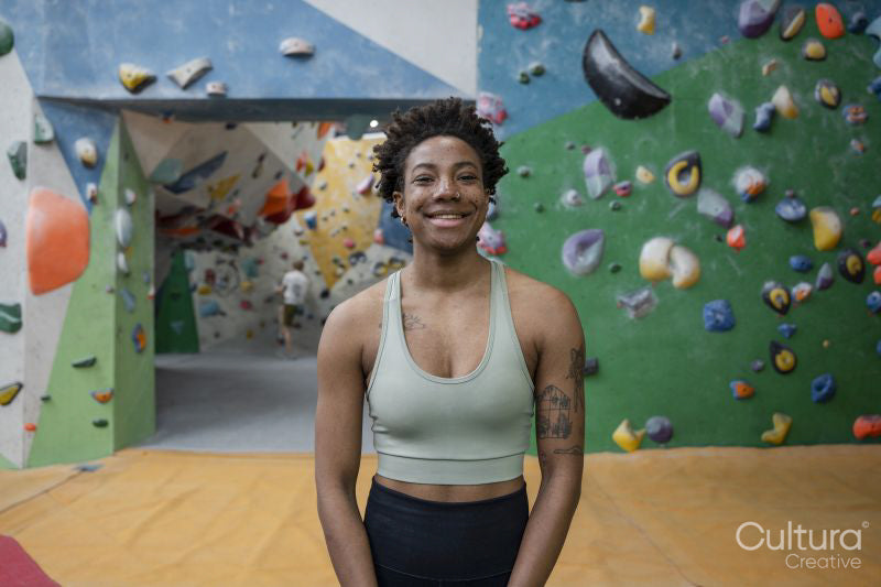 Portrait of smiling woman standing in front of climbing wall