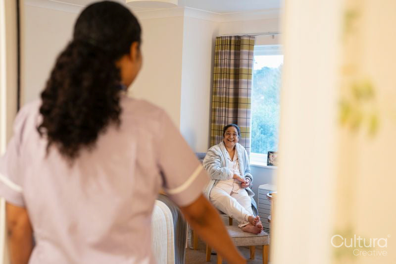 Nurse visiting senior lady in her room at nursing home