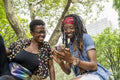 Two smiling young women looking at smart phone in park