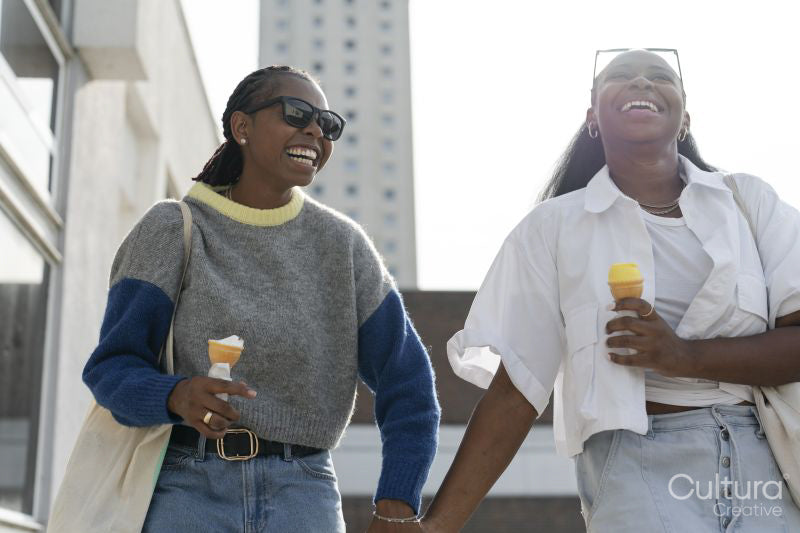 Young female couple walking in city and eating ice cream