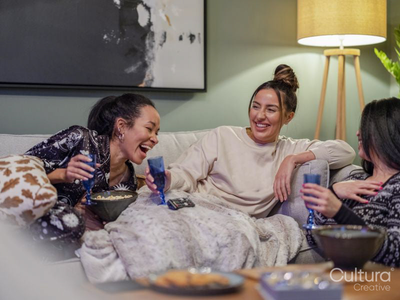 Friends laughing on sofa in living room
