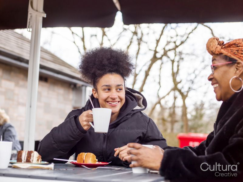 Mother with daughter sitting at outdoor cafe table