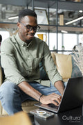 Young man with laptop sitting in office lounge