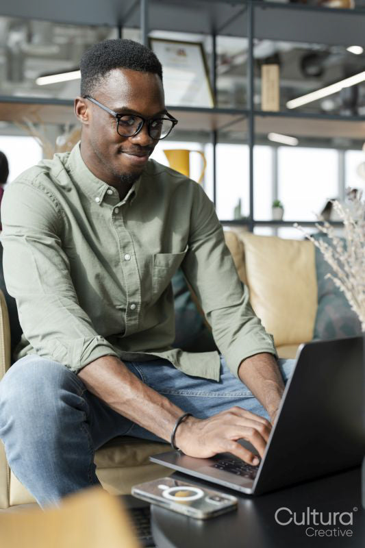 Young man with laptop sitting in office lounge