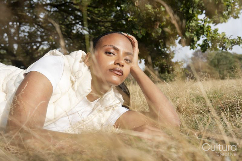 Portrait of young woman lying in grassy field