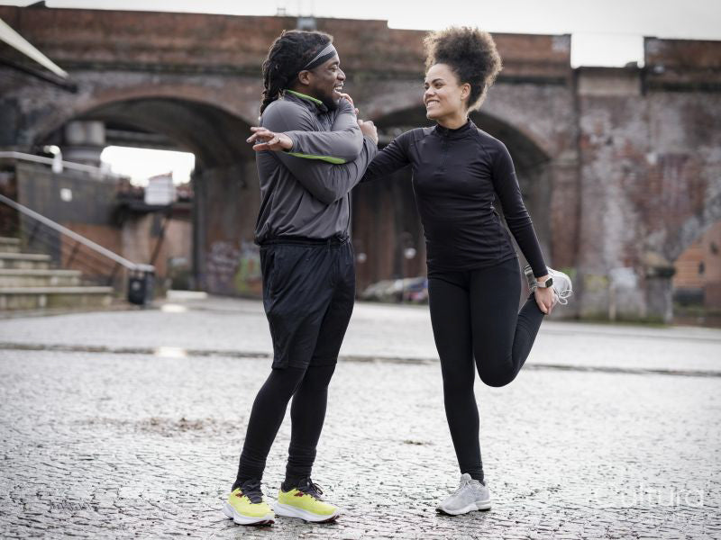 Athletic man and woman stretching outdoors