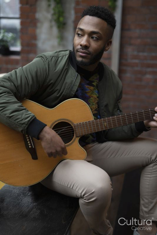 Young man playing acoustic guitar in office lounge