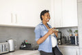 Smiling pregnant woman holding plate with red grapes in kitchen