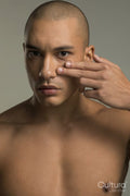 Studio portrait of serious shirtless man touching face